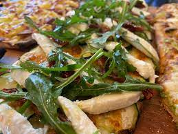 Pinsa con mozzarella fiordilatte, tonno, pomodori secchi, rucola e salsa yogurt