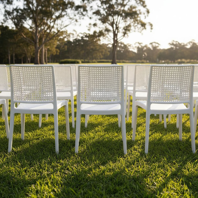 Оформление выездного мероприятия на открытом воздухе: легкие и устойчивые к погодным условиям стулья, расставленные на зеленом газоне для open-air формата.