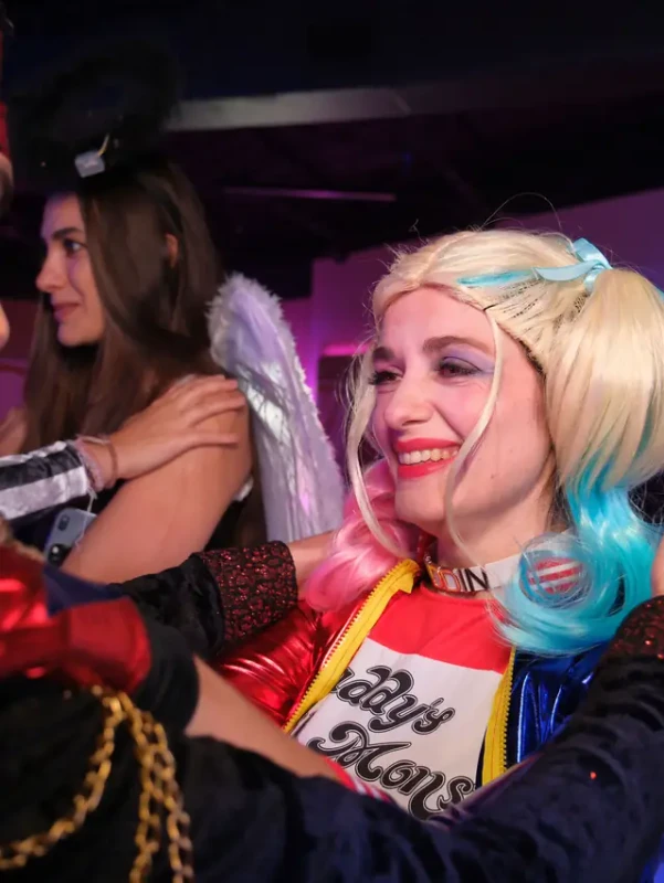 A guest in a pigtail wig laughing with friends