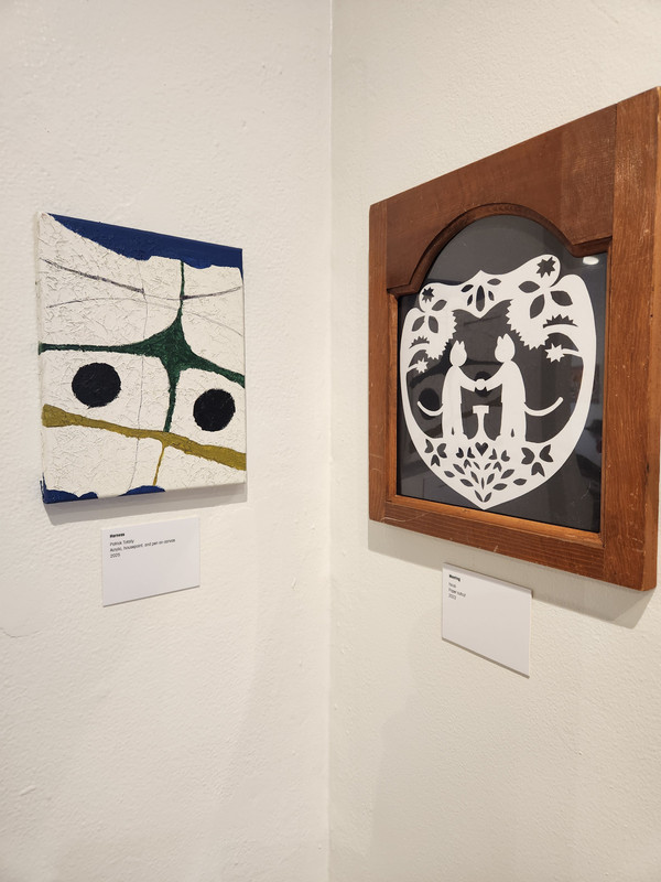 A canvas painting next to a framed shadowbox-style papercut work