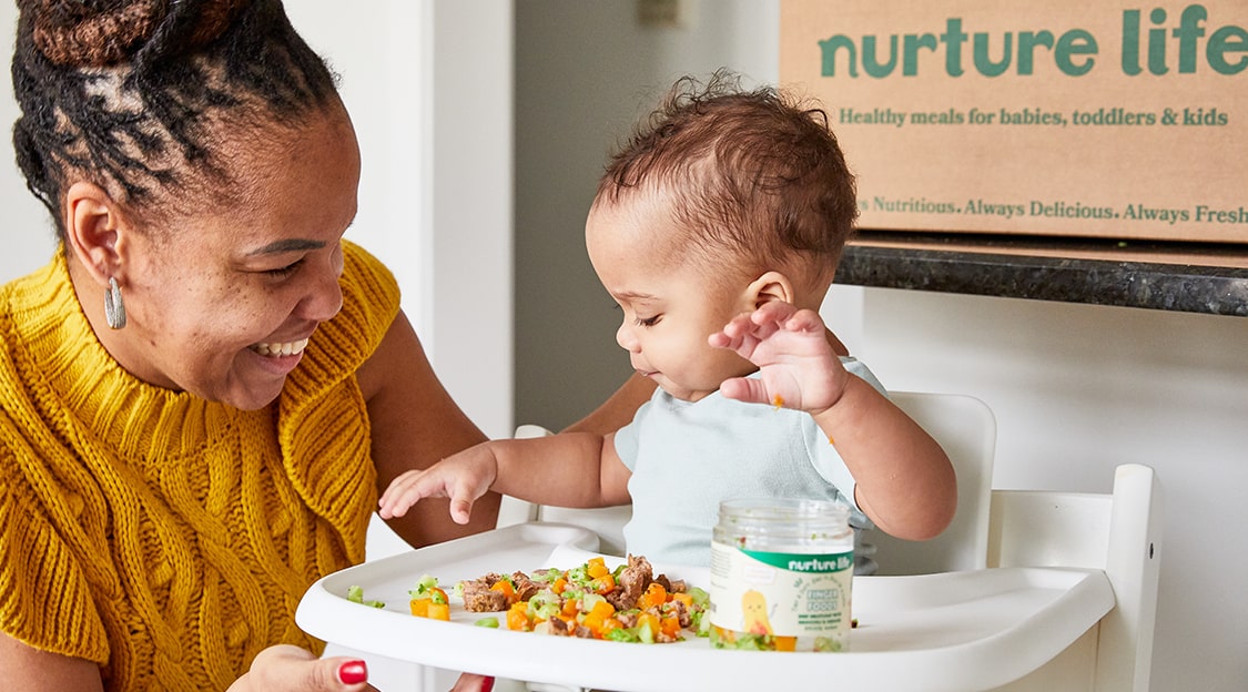 Close-up of a child happily eating a Nurture Life meal