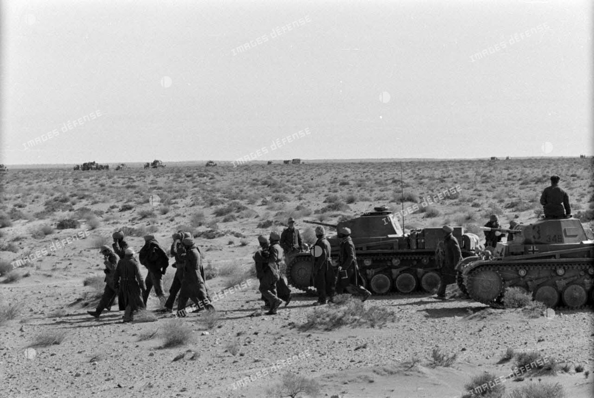 Des soldats britanniques d'une division indienne, prisonniers, dépassent deux Panzer II (Pz-II) du 3