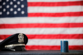 police hat and burning candling laying in front of American flag