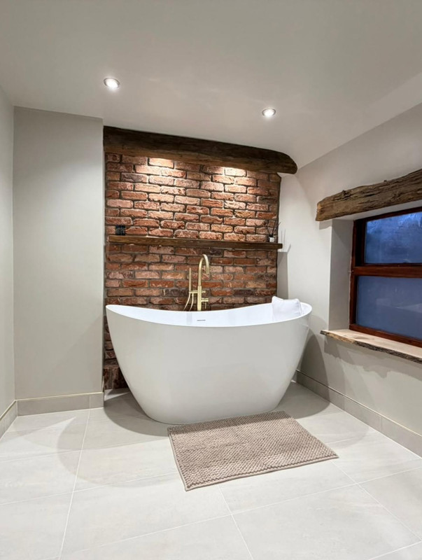 Freestanding bath with exposed brick wall and rustic window detail