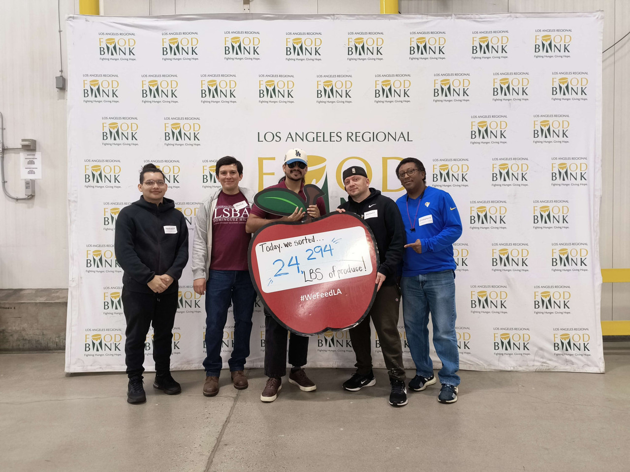 LSBA volunteers at the Los Angeles Regional Food Bank holding a large apple display.