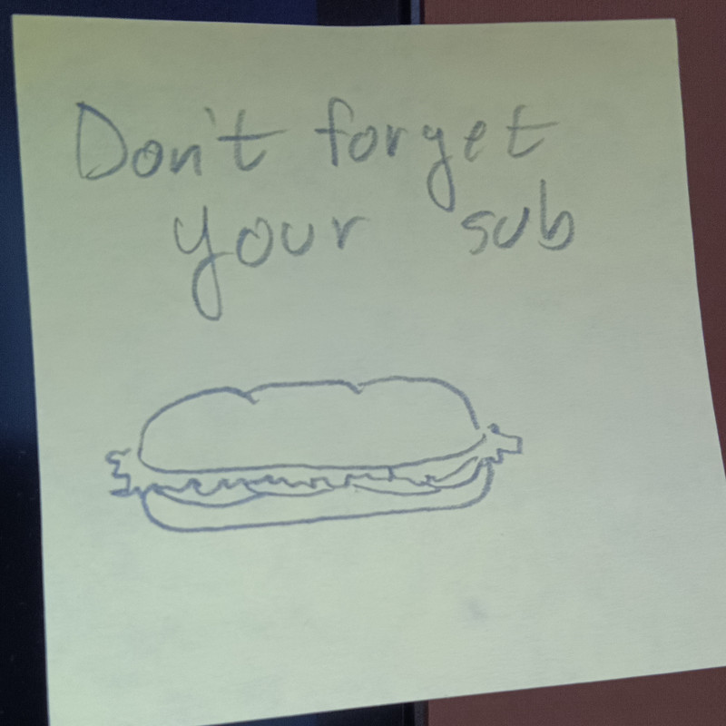 A post it note reading "Don't forget your sub" with a sketch of a sub sandwich.