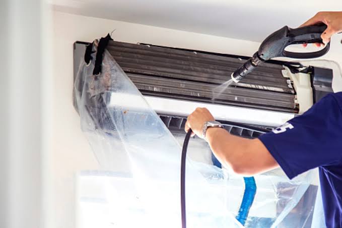 Técnico realizando a limpeza do ar-condicionado