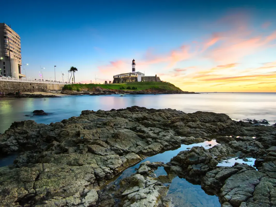 O Farol da Barra em um dia ensolarado, com o mar azul ao fundo.