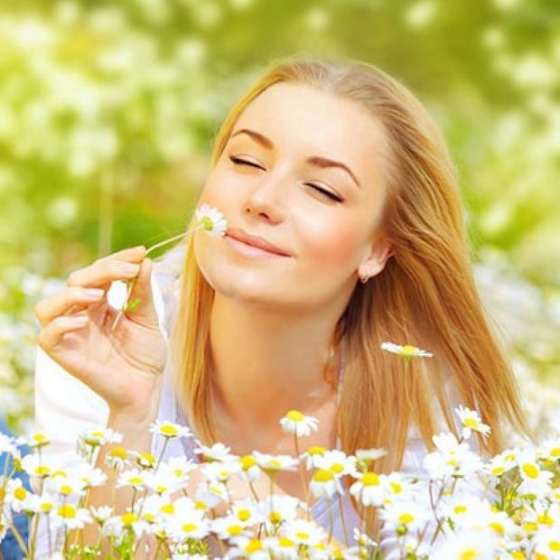 Devojka na livadi u proleće miriše cveće