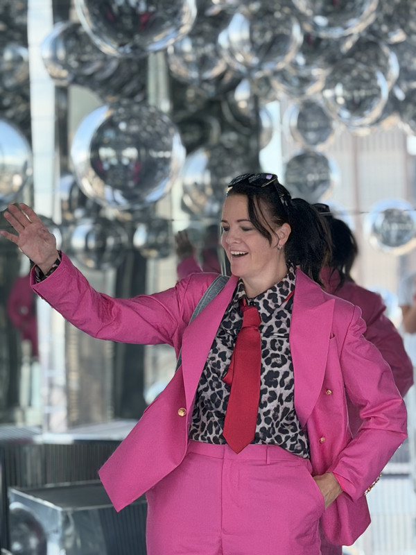 Gin, pink blazer, arm raised