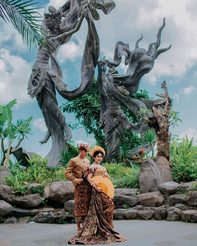 Bak negeri dongeng, pasangan ini berfoto dengan latar belakang patung bidadari di Taman Dedari.