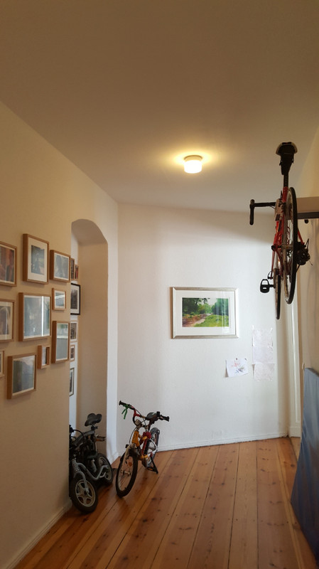 Privater Eingangsbereich in der Inselstraße mit warmer Deckenbeleuchtung, Holzboden und Bilderwand