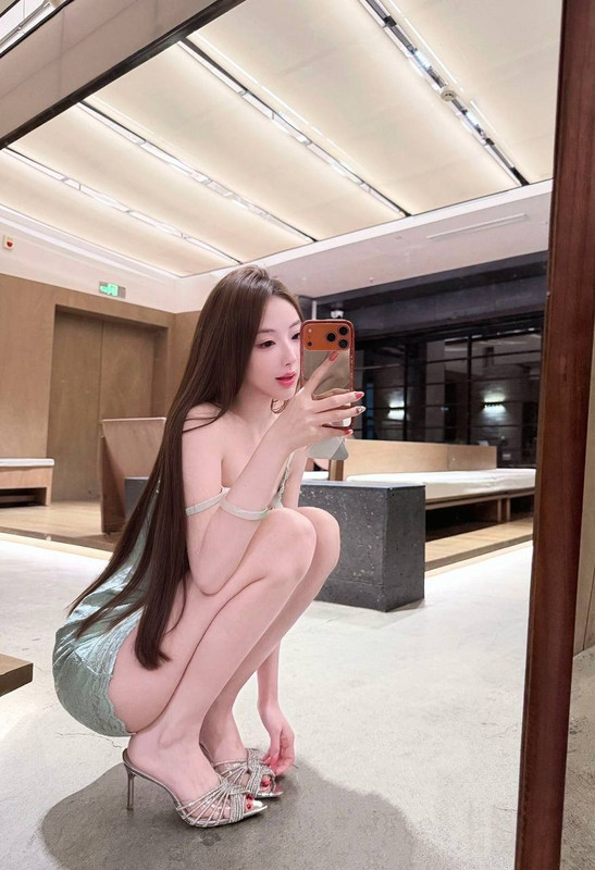 桃園外送茶長髮女子穿淺綠色造型服裝、搭配高跟涼鞋，在室內蹲姿自拍