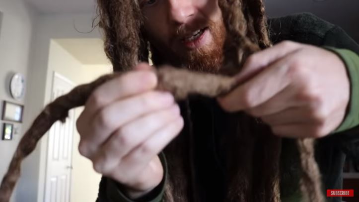 pria ini menunjukkan debu di rambut gimbalnya
