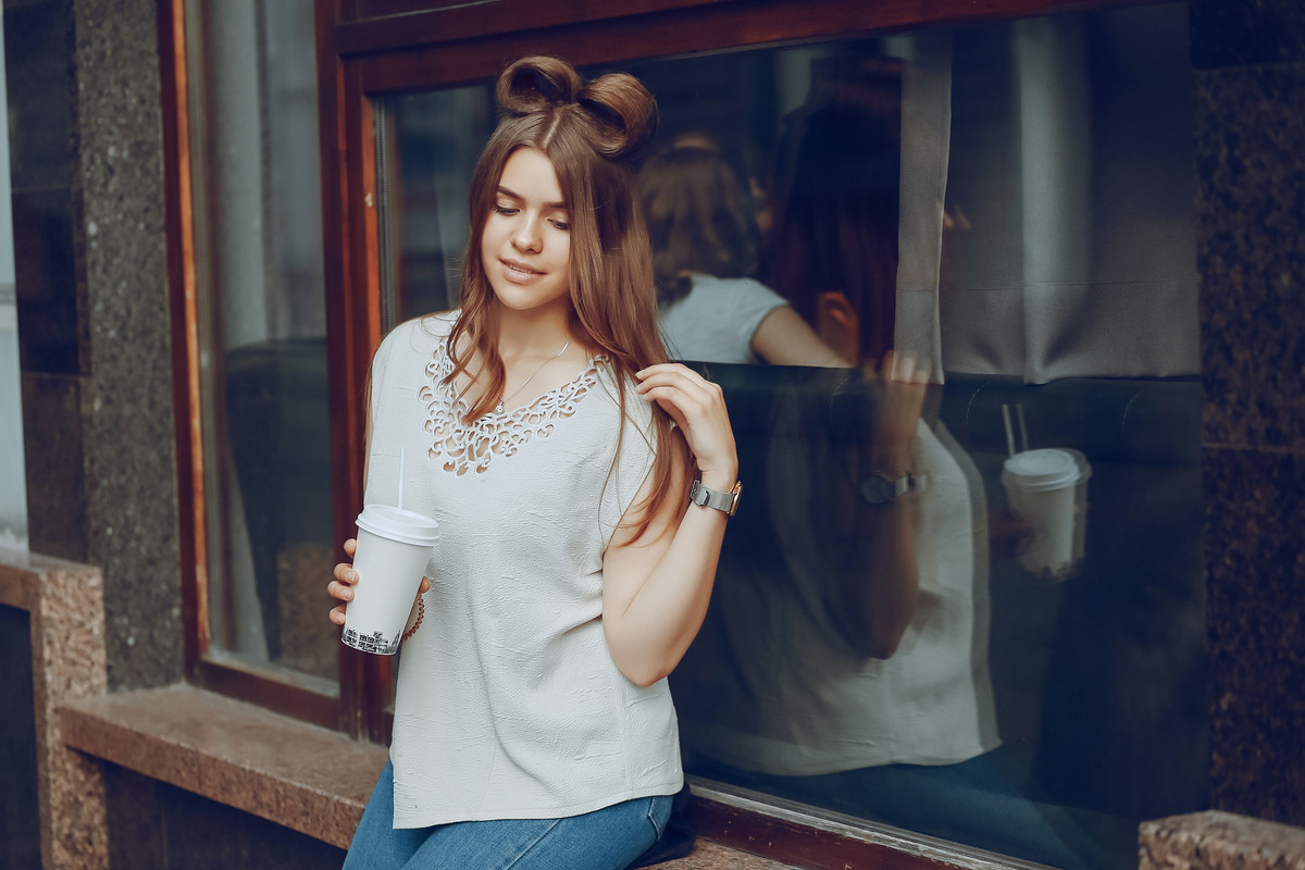Femeie savurant o cafea si este imbracata intro bluza simpla dama