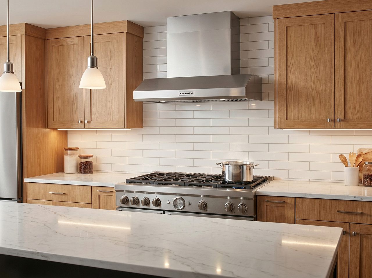 Campana extractora KitchenAid de estilo comercial instalada sobre una estufa profesional en una cocina de alta gama