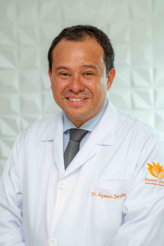 Retrato profissional do Dr. Alysson Zanatta com jaleco médico em fundo branco.