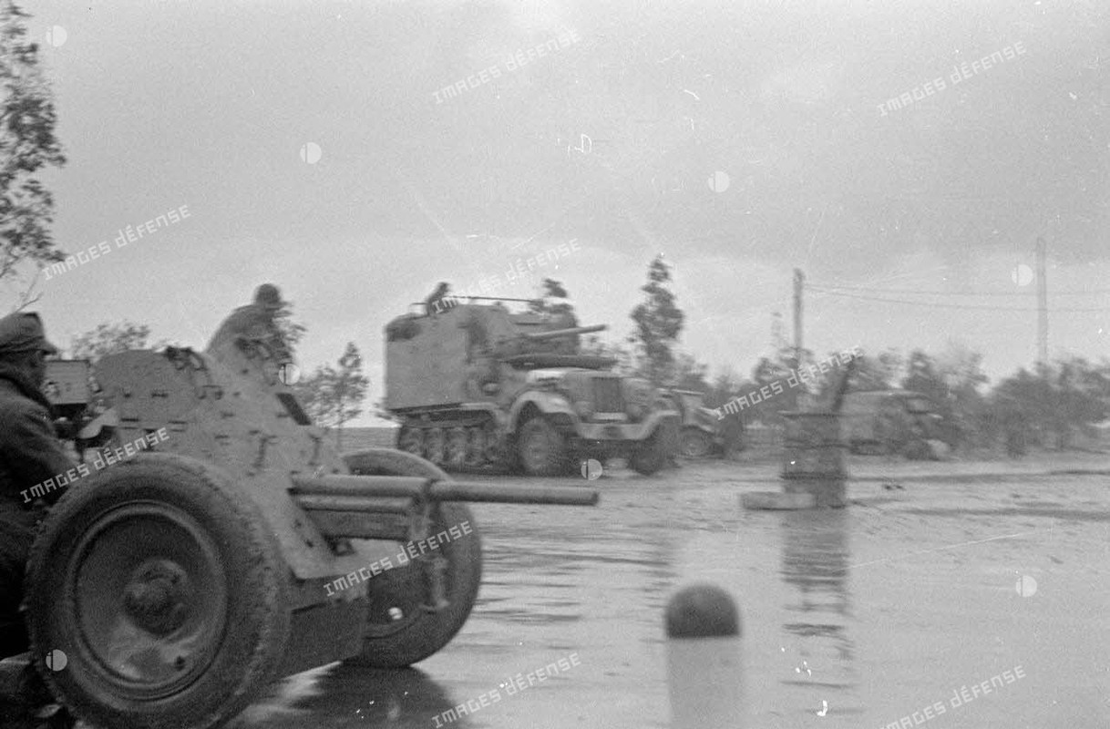 Au premier plan, canon de 3,7 cm PaK puis un semi-chenillé Sd.Kfz-6 transformé en véhicule blindé mu