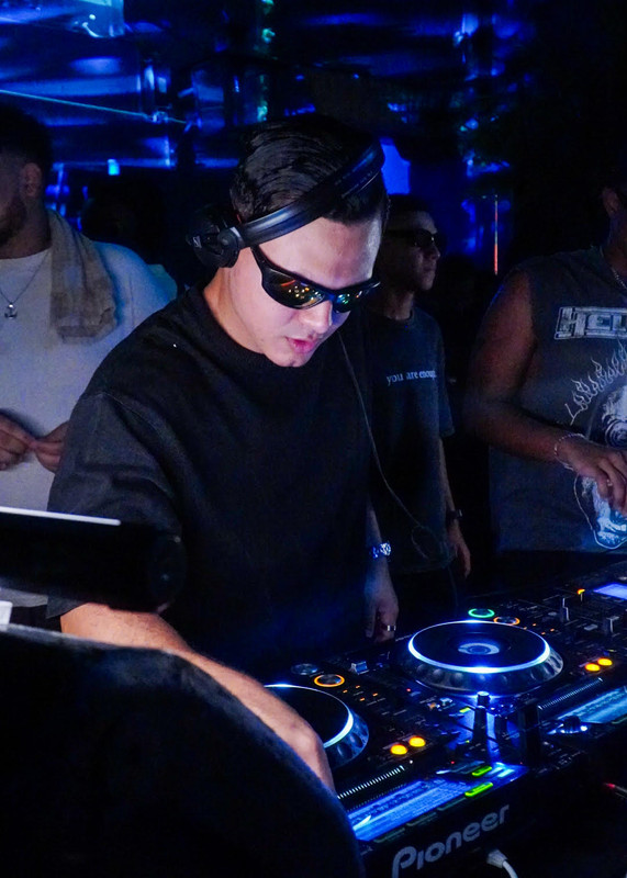 DJ Cj Hawk performing at cyberpunk party with neon lights and futuristic setup