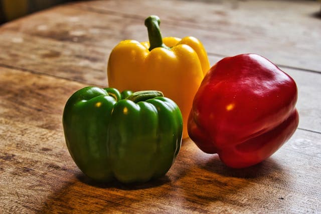 Red, green and yellow bell pepper on a table