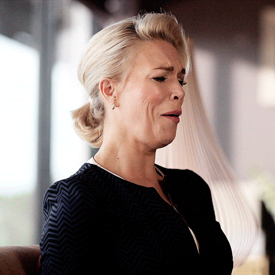 Rebecca looks on in surprised and delighted amusement from her office couch.
