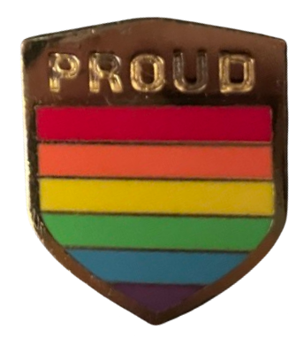 a gold enamel pin in the shape of a shield, with the words 'PROUD' engraved in the top and a rainbow filling the rest of it