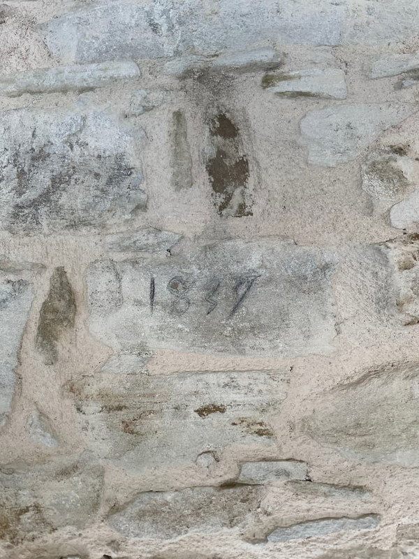 A wall made of stones, light greyish. The one in the middle has 1839 visibly carved. It has been brushed up with a pencil.