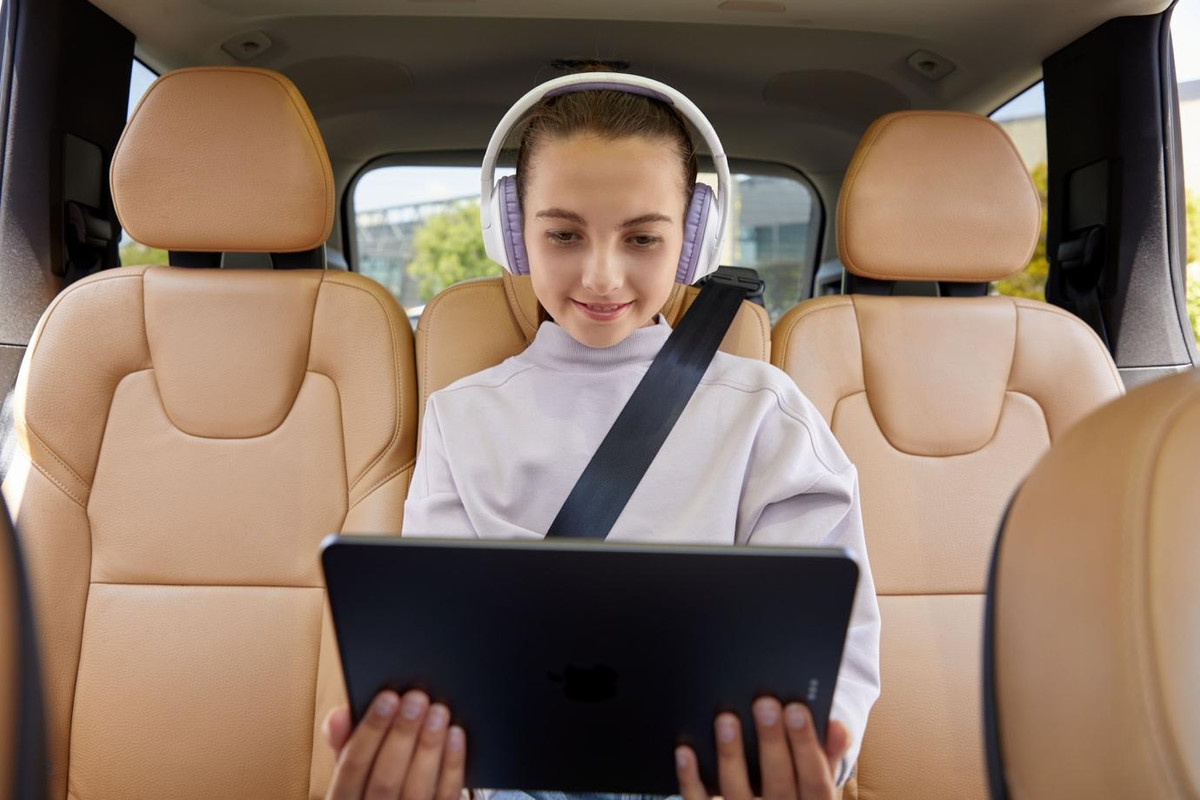 A child sitting in a car with a tabletDescription automatically generated