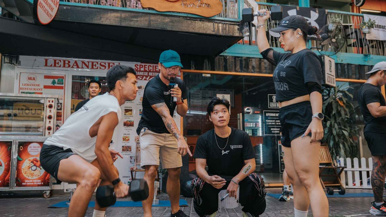 Người tập nâng tạ đơn (dumbbell) ngoài trời trong buổi tập nhóm cộng đồng