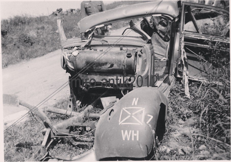 Разорванный немецкий легковой автомобиль у обочины дороги, который был запечатлён на фотокамеру воен