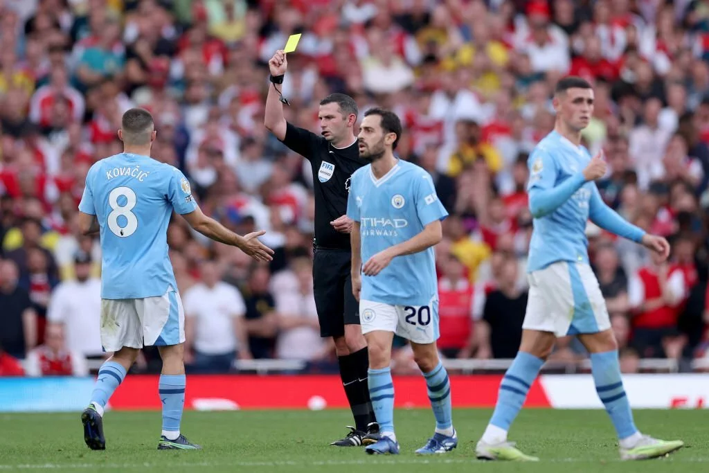 Michael Oliver showing a yellow to Mateo Kovacic