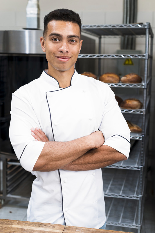 portrait young male baker with his arms crossed looking camera