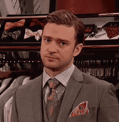 a-man-in-a-suit-and-tie-is-standing-in-front-of-a-closet-filled-with-ties-a27r1yage27q65yr.gif