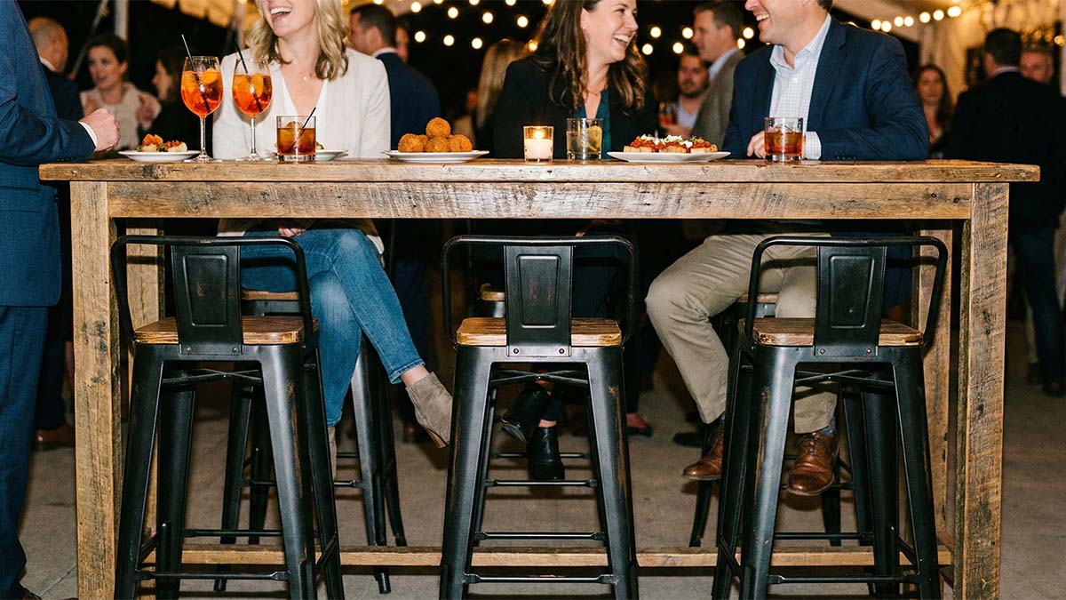 Стильные высокие барные стулья у деревянного стола, акцент на удобную перекладину для ног.