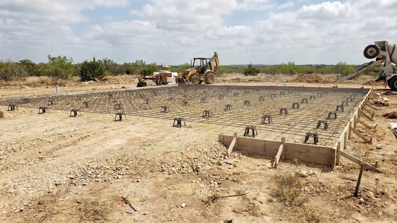Welded wire mesh sitting on plastic chairs elevated above compacted base on a San Antonio patio slab project showing correct mid-depth steel placement before the concrete pour