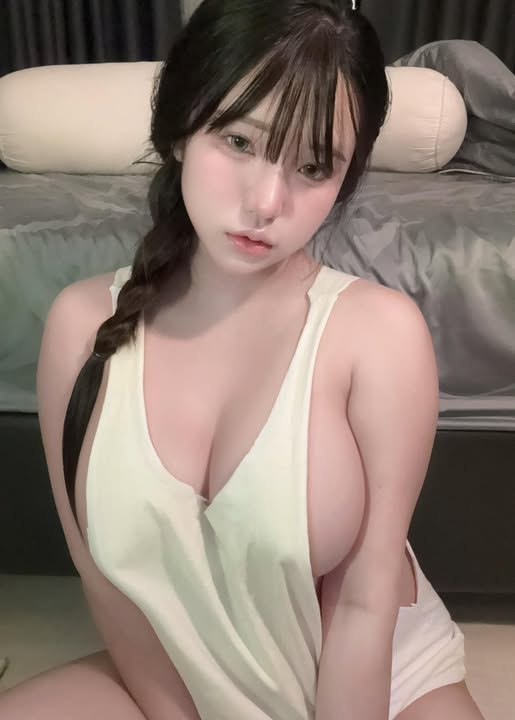綁辮子女生穿淺色低胸上衣坐在床邊拍照