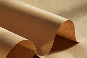 A large roll of brown Kraft paper ready for industrial use.