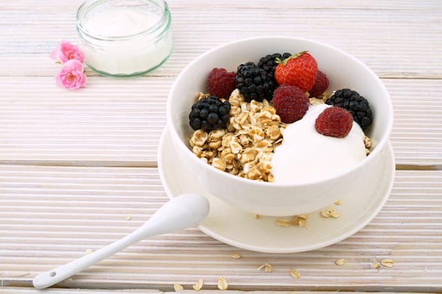 Bowl of oatmeal topped with fresh berries and milk, a fiber-rich breakfast that supports gut health and digestion.