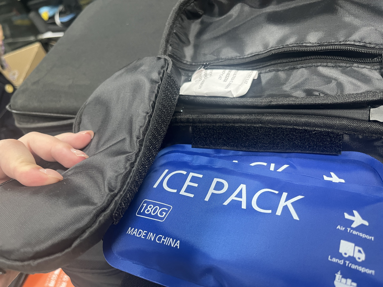 Custom hard EVA insulin cooler case open on a wooden table, showing a middle divider panel with elastic straps holding insulin pens, a dedicated ice pack compartment, and internal mesh pockets in a warm home background.