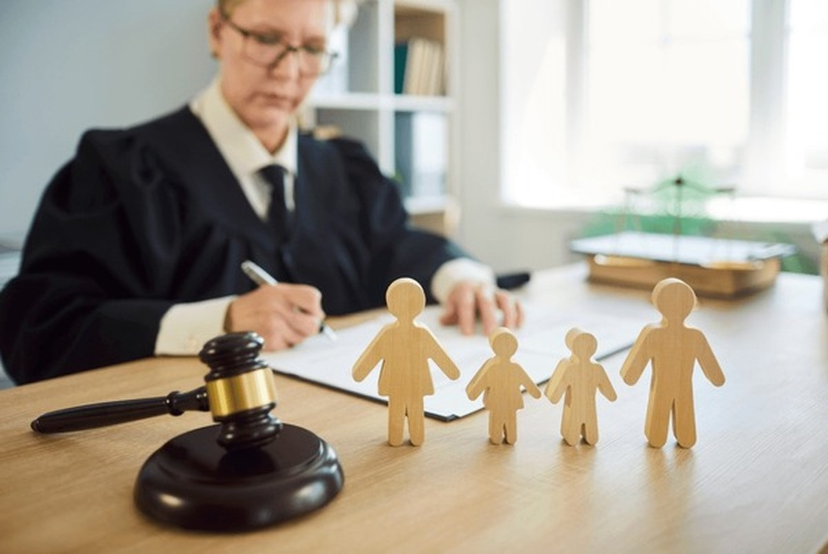 Family lawyer in Melbourne - judge writing at her desk with a gavel and wooden family figures displayed on the desk.
