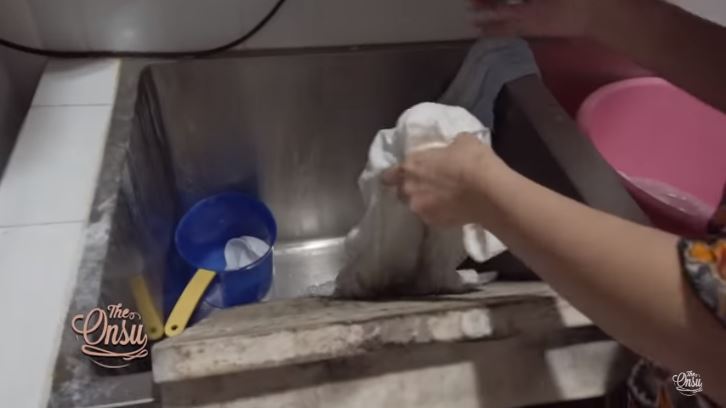 Sarwendah mencuci menggunakan papan penggilasan kayu.