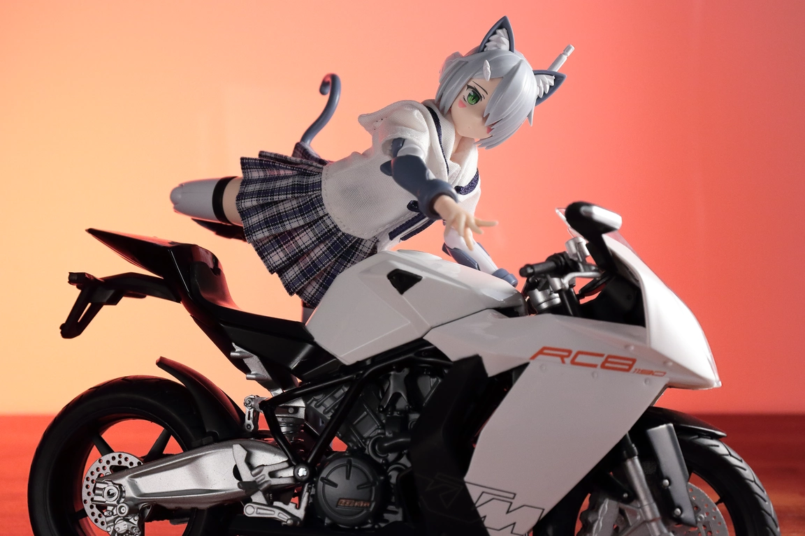 A right-side view of a 1:12 scale diecast model of the RC8 in white and “Variable Fighter Girls” Kairos girl wearing a 1/12 White Collar Check Sailor Uniform Set in blue