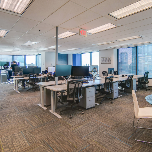 Multiple rows of coworking chairs and desks in large area