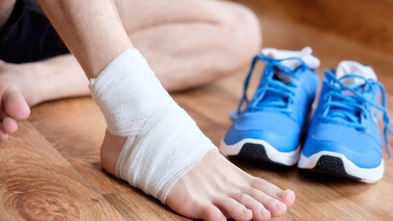 Mắt cá chân được băng ép, đôi giày thể thao để cạnh chưa sử dụng trong giai đoạn phục hồi