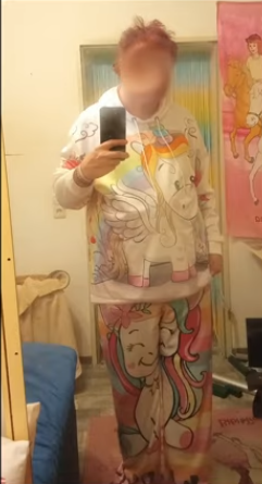 a selfie of the frumpy overweight cuntsuela with their face edited out in a bizzare swirl wearing a 2 piece sweat suit that was definetly designed for small children featuring unicorns and rainbows the artstyle is very simple and childish with almost no detail or color besides white its very white with a little bit of ugly pastel yellow