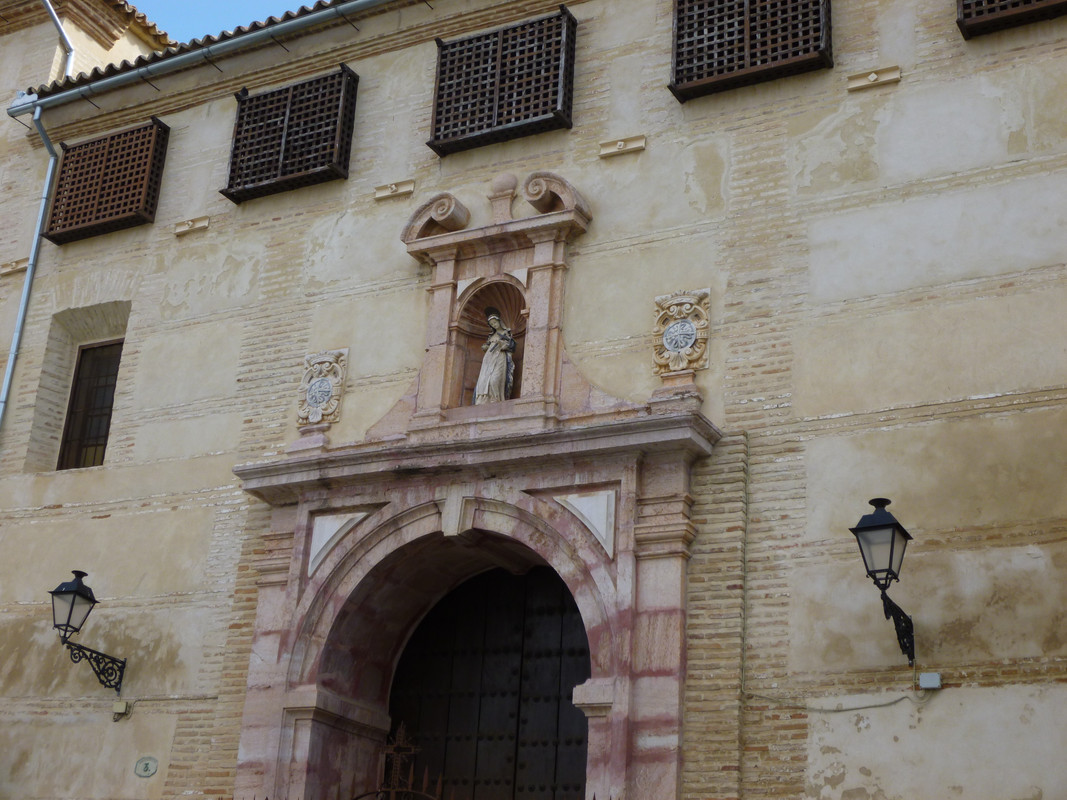 Thick wooden church door with a niche above it.  In the niche is a statue of the Virgin Mary.