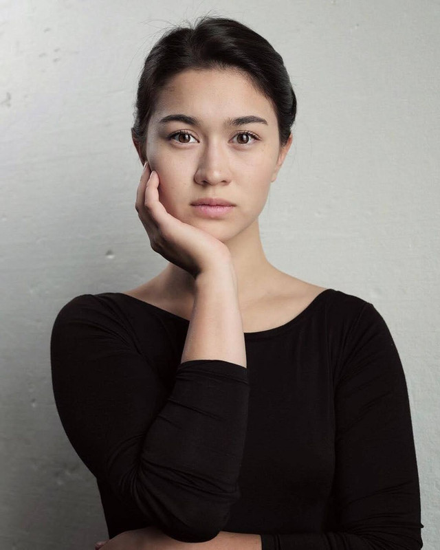 A picture of Beatrice posing thoughtfully in a black shirt with her hair in a bun.