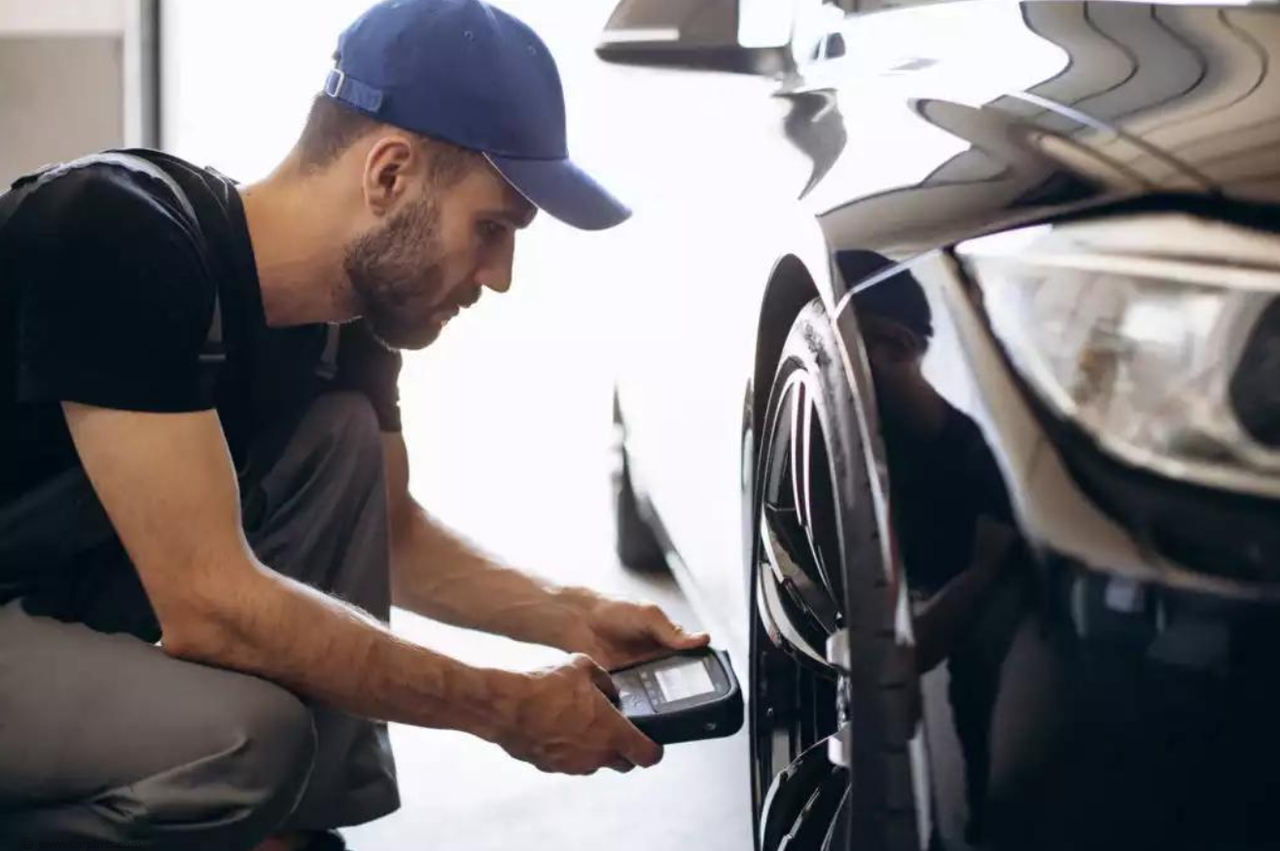 `Technician uses TPMS tool to activate tire pressure sensor in auto repair shop`
