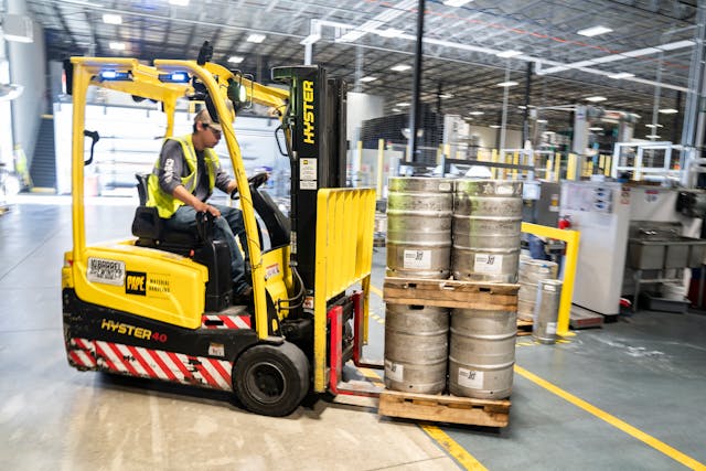 Warehouse worker operating forklift in organized storage facility