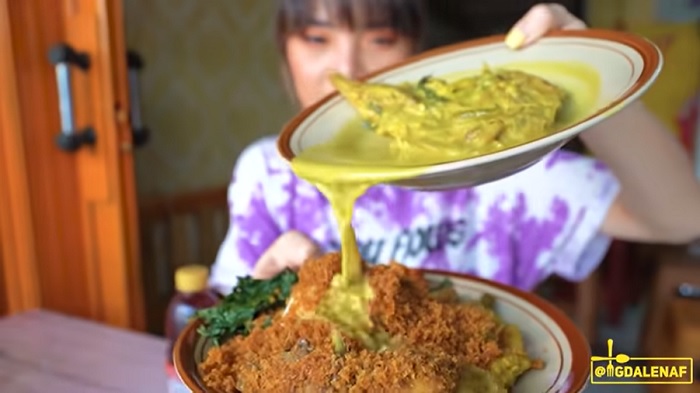 Magda saat menyiram kuah kakap di nasi Padang.